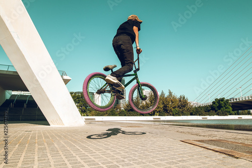 Guy tricking a BMX bike down the street. Concept of street sports
