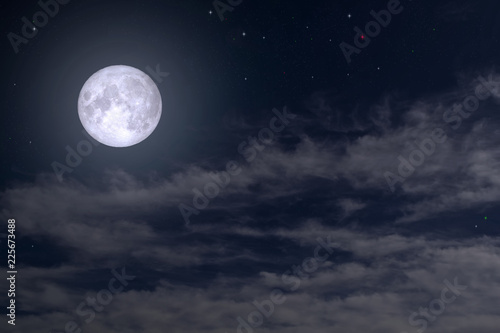 The full moon between the clouds in the night sky