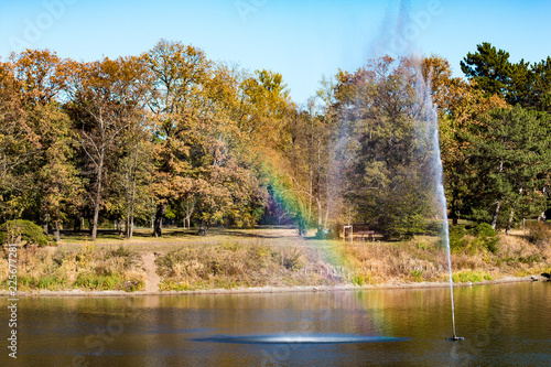 Lake with fountain and rainbow in the park in autumn © Matthias