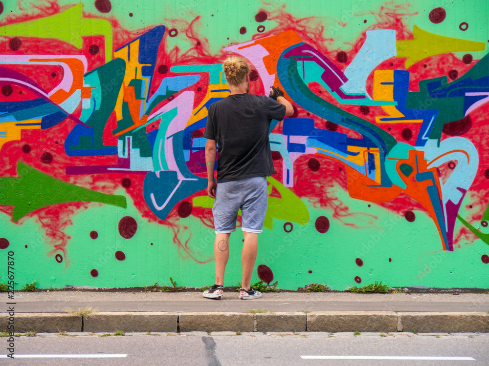 Obraz premium young man use his talent and feeling for art to apply this with various colors to a city wall