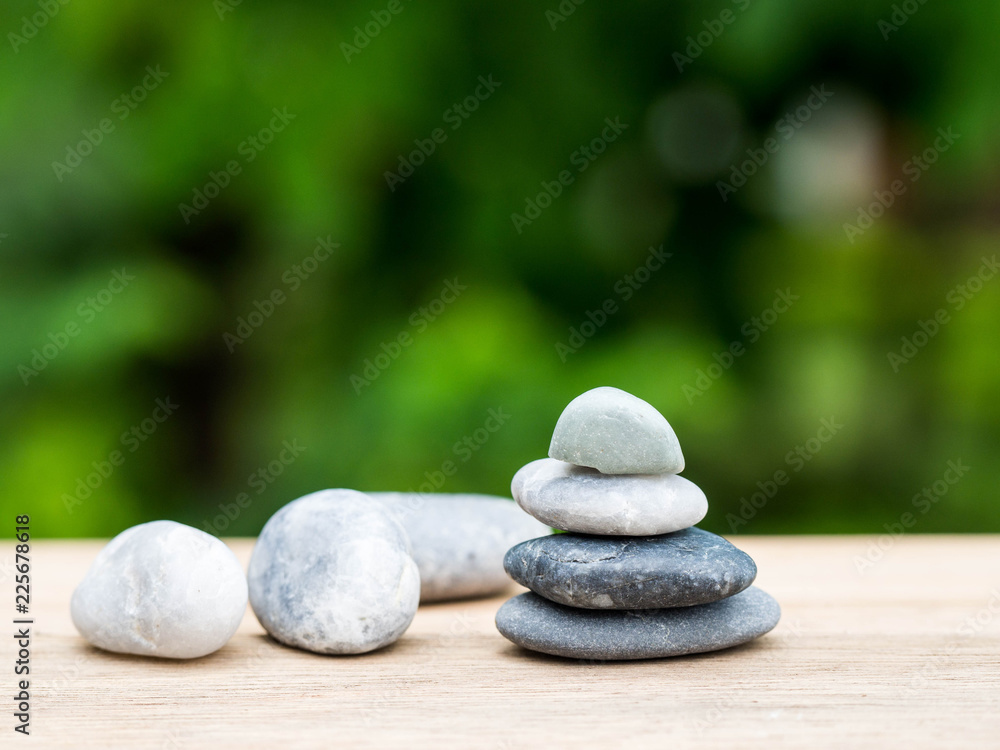 Four stones stacked placed on a wooden board. The backdrop is black on green.
