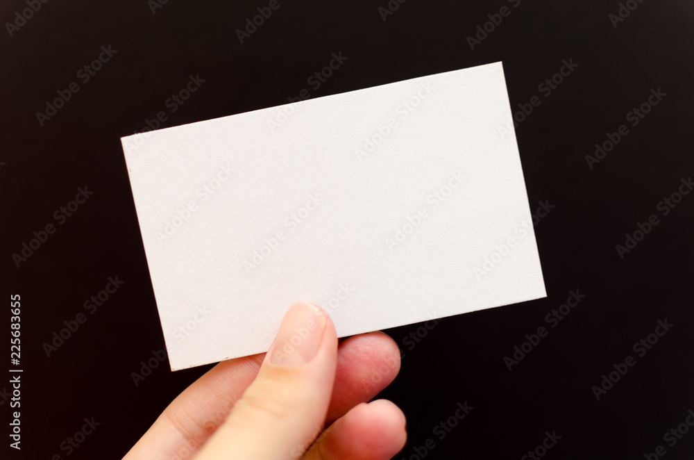 Hand holding a blank business card on a black background Hand holding a blank business card on a black background