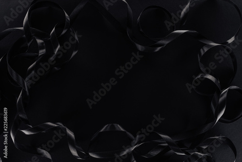 top view of glossy ribbons on black background with copy space for black friday