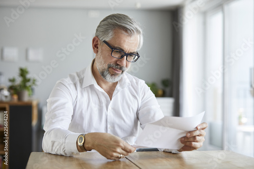 Portrait of mature man reading letter at home photo