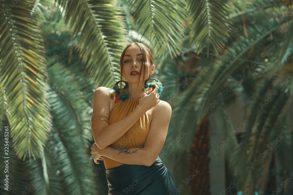 Naklejka premium Stunning fit woman among tropical plants posing