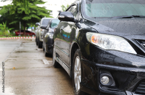 Closeup of front side of modern black car park in parking area in rainy day.  © Amphon