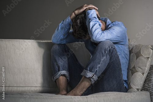 young attractive and handsome sad latin man sitting tired and depressed at home sofa couch feeling overwhelmed and worried suffering depression crisis and anxiety © TheVisualsYouNeed