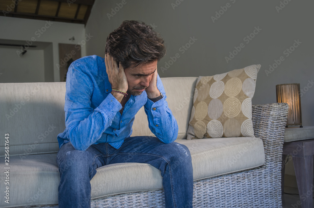 young attractive and handsome sad latin man sitting tired and depressed at home sofa couch feeling overwhelmed and worried suffering depression crisis and anxiety young attractive and handsome sad latin man sitting tired and depressed at home sofa couch feeling overwhelmed and worried suffering depression crisis and anxiety