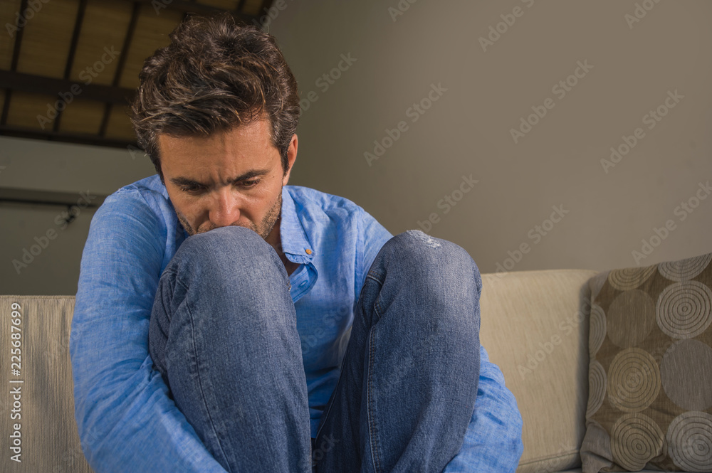 young attractive and handsome sad latin man sitting tired and depressed at home sofa couch feeling overwhelmed and worried suffering depression crisis and anxiety young attractive and handsome sad latin man sitting tired and depressed at home sofa couch feeling overwhelmed and worried suffering depression crisis and anxiety