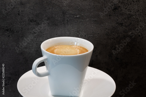 Eine Tasse cremiger Kaffee vor einer strukturierten Steinwand