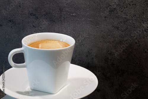 Eine Tasse cremiger Kaffee vor einer strukturierten Steinwand