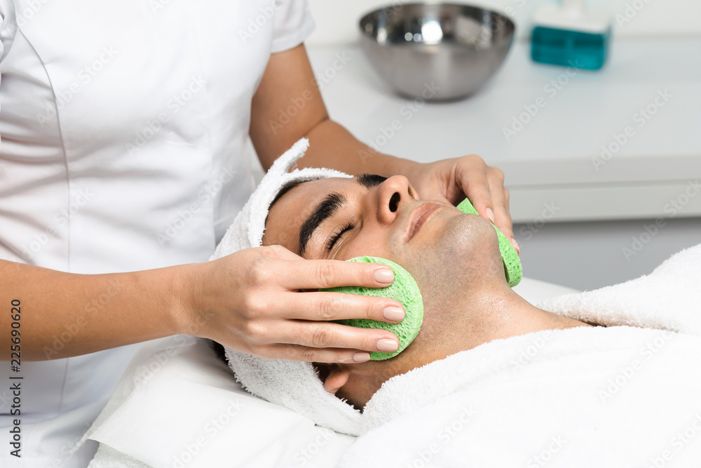 Male cosmetics. Good looking man receiving face treatment at luxury spa.