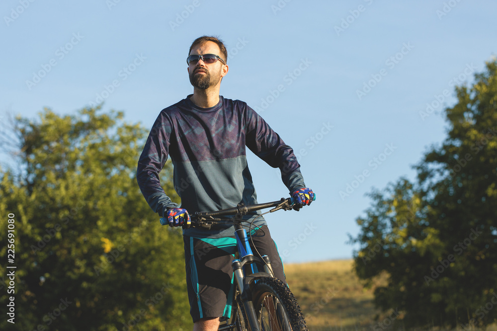 Naklejka premium A cyclist rides the hills, Beautiful portrait of a guy on a blue bicycle