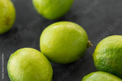food, healthy eating and vegetarian concept - close up of whole limes on slate table top
