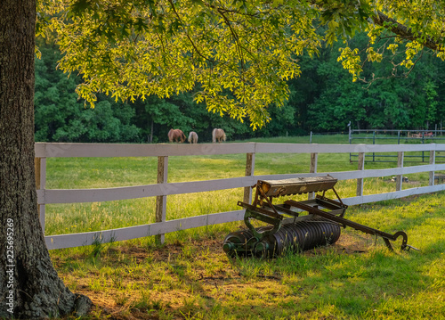 La Plata, Maryland, USA - May 11, 2018: Sunset on the farm with a plow in front of a fence