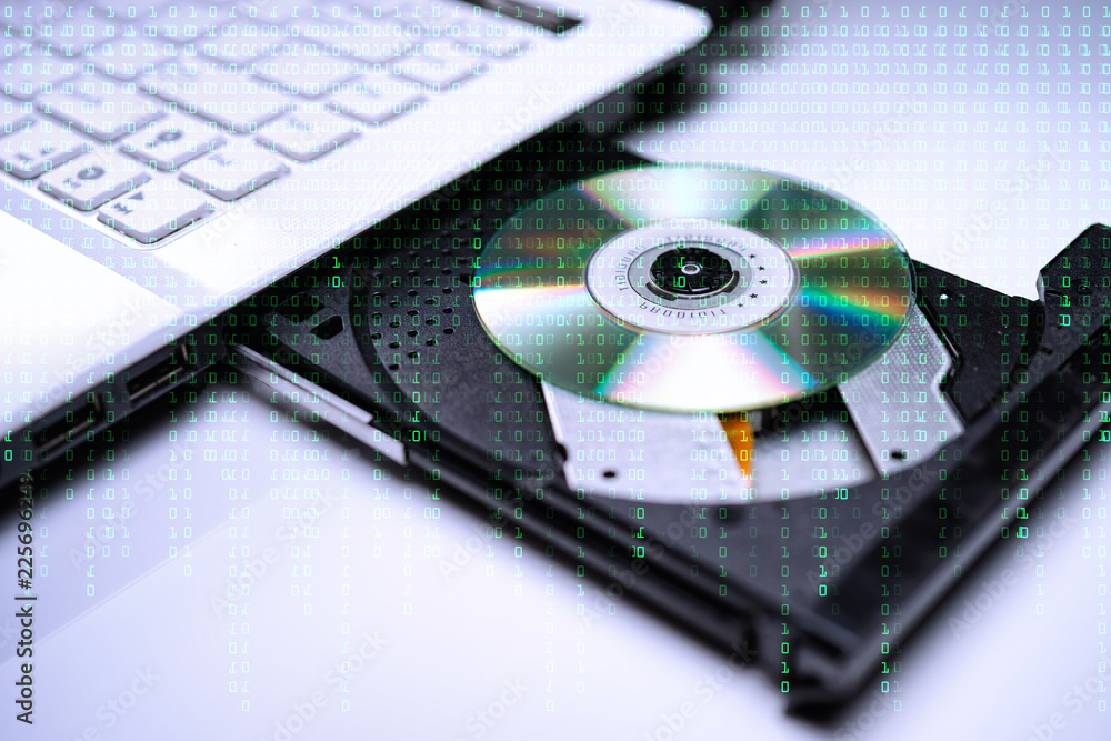 DVD Disk on the white Laptop DVD ROM Tray with a Man Hand. A Piracy conceptual image of burning data into DVD Disk DVD Disk on the white Laptop DVD ROM Tray with a Man Hand. A Piracy conceptual image of burning data into DVD Disk