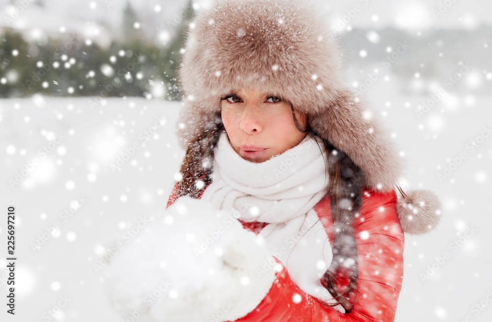 people, season and leisure concept - happy woman in winter fur hat blowing on snow in her hands outdoors people, season and leisure concept - happy woman in winter fur hat blowing on snow in her hands outdoors