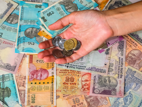 Woman's hands holding coins over 10, 20, 50, 100, 200, 500 and 2000 Indian rupees, old and new notes.