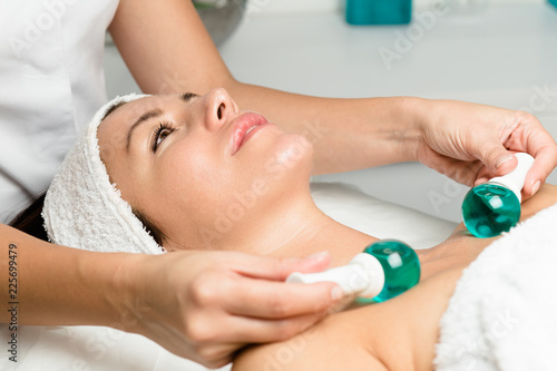 Beautiful woman in beauty salon during treatment with a cold glass balls. Cryo therapy. Face and skin care.