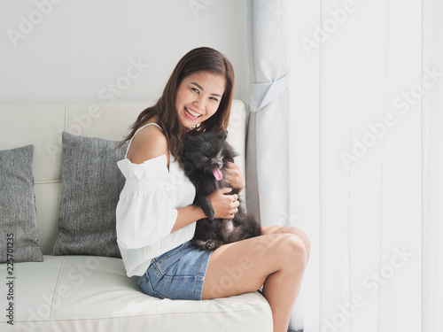 Tableau sur toile Asian woman playing with little dog black color in living room lifestyle girl wi