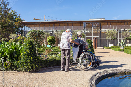 An old woman walking in the Park of her disabled husband on a wheelchair