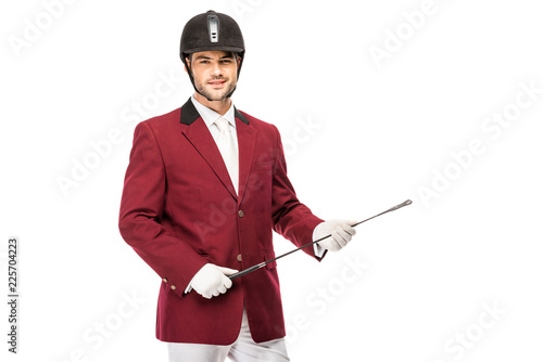 Tableau sur toile smiling young horseman in uniform holding horseman stick and looking at camera i