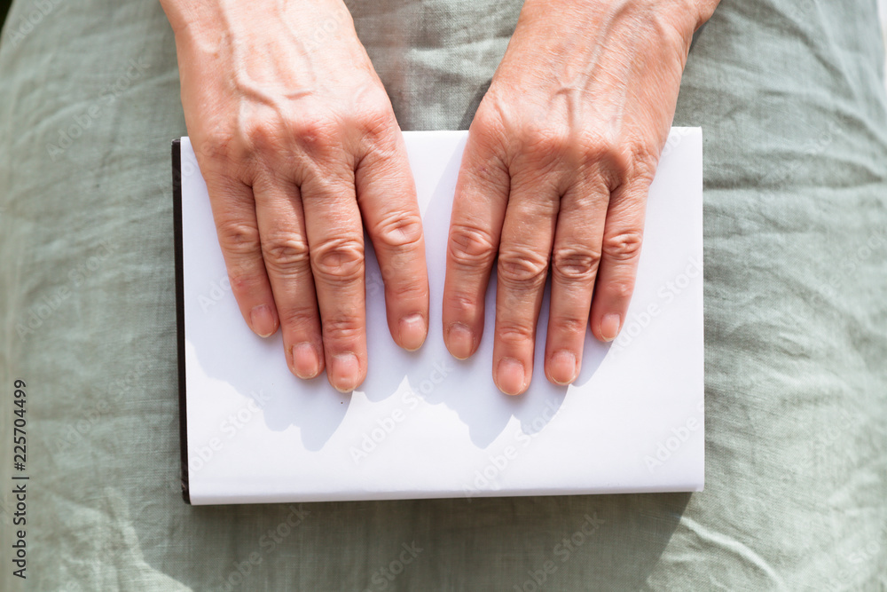 Hands hold the book below about legs Hands hold the book below about legs