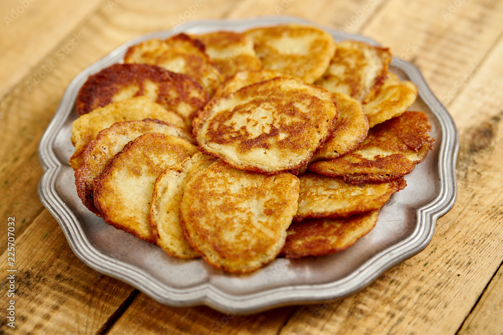 metal plate with delicious potato pancakes on an old wooden kitchen table