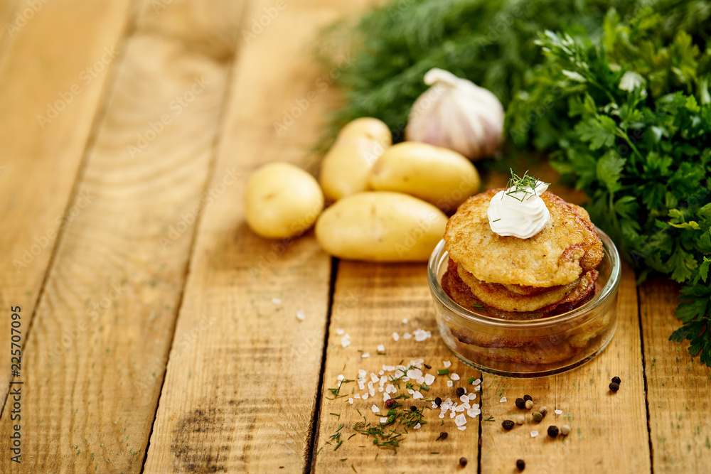 small bowl with potato pancakes on an old wooden table with garlic and parsley in the kitchen small bowl with potato pancakes on an old wooden table with garlic and parsley in the kitchen