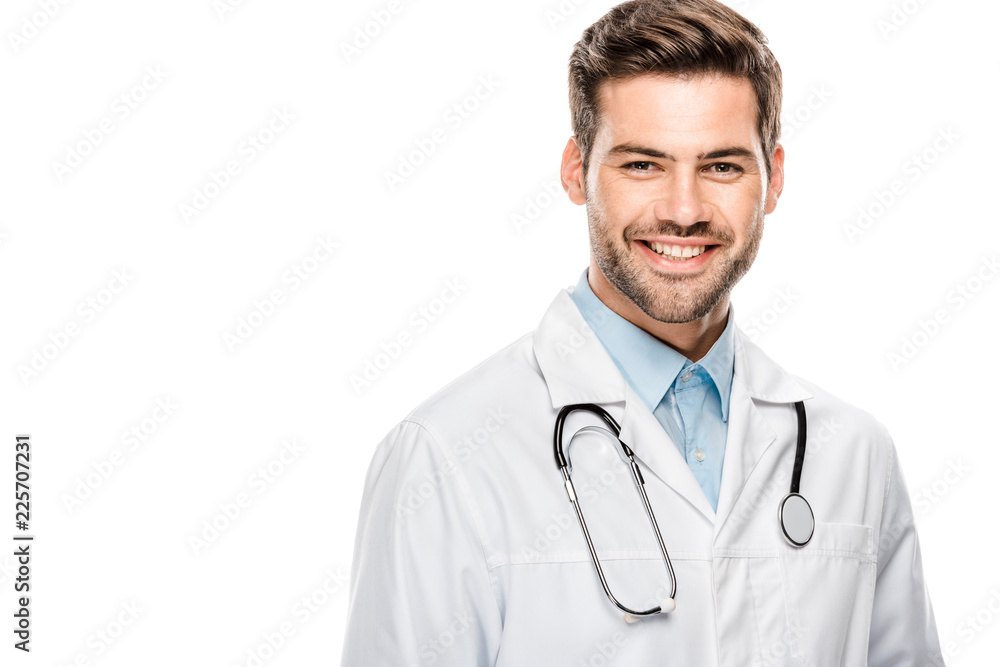 happy male doctor in medical coat with stethoscope over neck looking at camera isolated on white