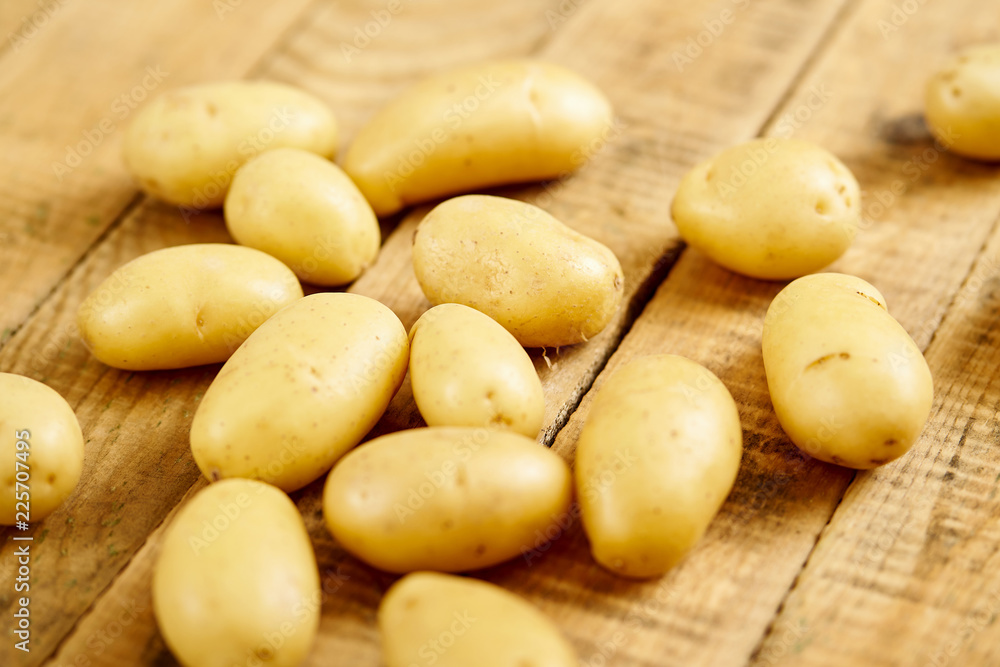 lots of fresh and young potatoes on an old wooden table in the kitchen lots of fresh and young potatoes on an old wooden table in the kitchen