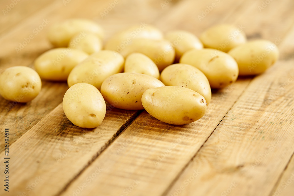 lots of fresh and young potatoes on an old wooden table in the kitchen lots of fresh and young potatoes on an old wooden table in the kitchen
