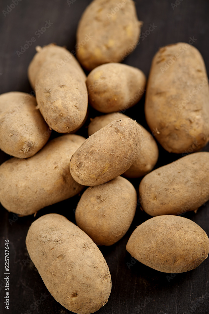 lots of young and fresh potatoes on a black wooden table in the kitchen lots of young and fresh potatoes on a black wooden table in the kitchen