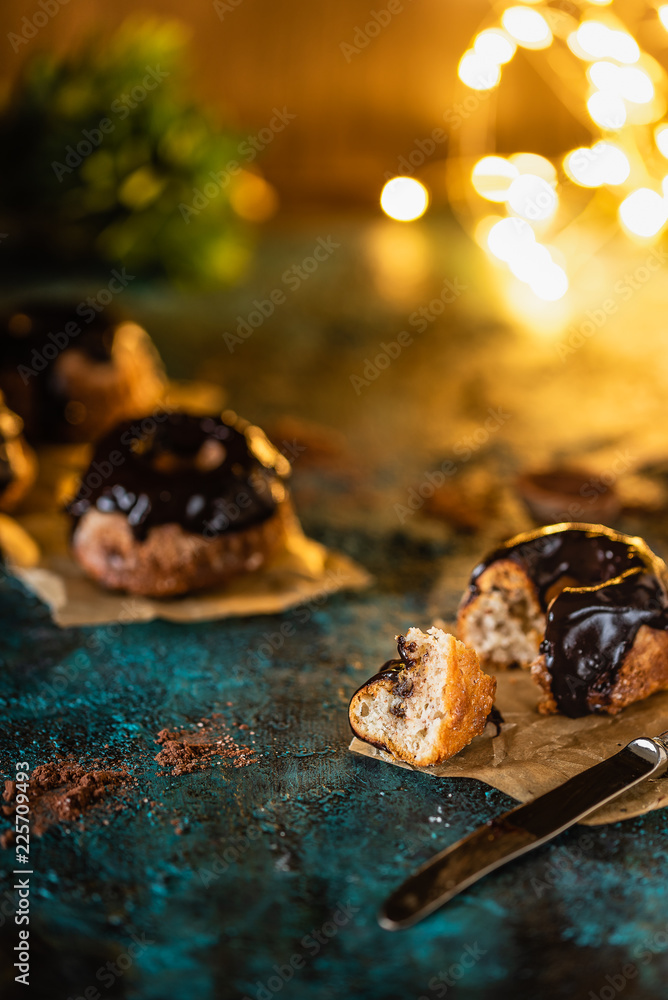 small ricotta cakes with chocolate icing, in Christmas atmosphere. Christmas lights in the background 