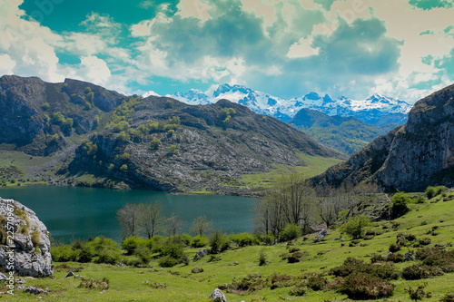 View of one of the Lakes of Covadonga, Picos de Europa National Park, Spain, with snow-covered mountains in the background.