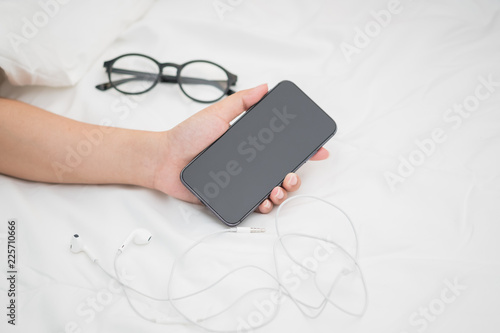 Woman sleeping and holding a mobile phone on the bed in bedroom