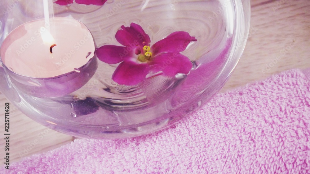 Romantic composition with a candle and violet flowers floating in a bowl of water.The concept of Spa,cosmetic,procedure,treatment. Romantic composition with a candle and violet flowers floating in a bowl of water.The concept of Spa,cosmetic,procedure,treatment.