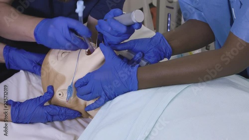 Endotracheal intubation training procedure being carried out on a medical mannequin in a university hospital.