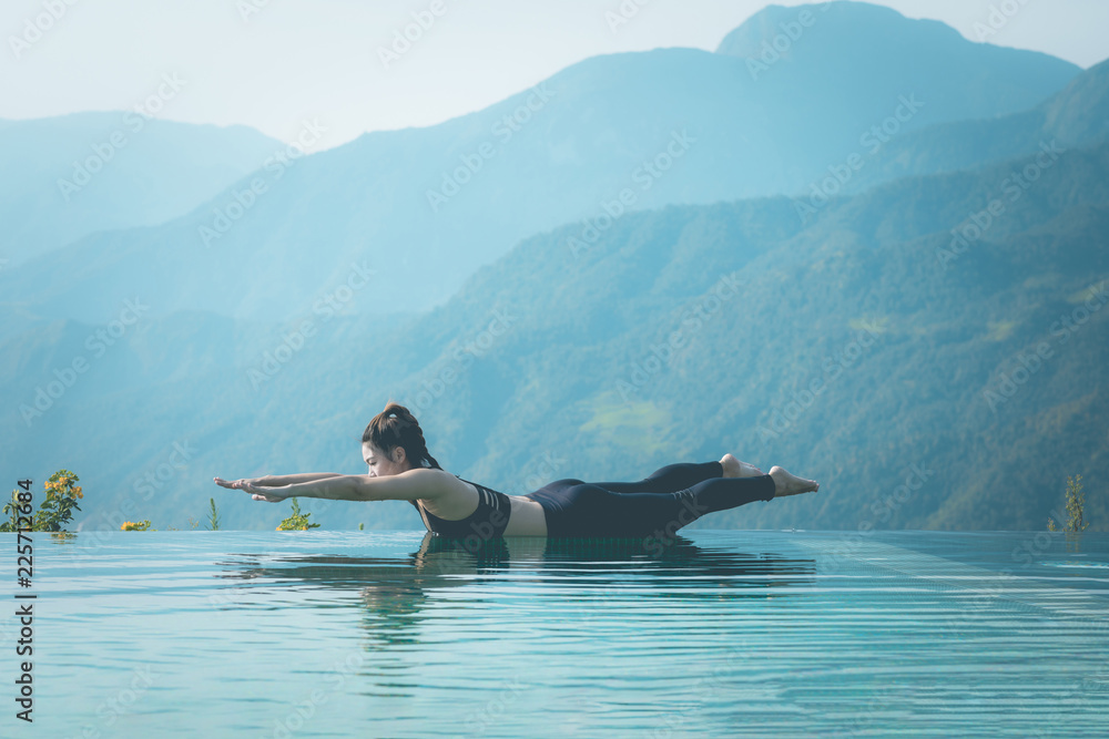 © 220 Selfmade studio - Beautiful Attractive Asian woman practice yoga Locust or Shalabhasana pose on the pool above the Mountain peak in the morning in front of beautiful nature views in SAPA vietnam