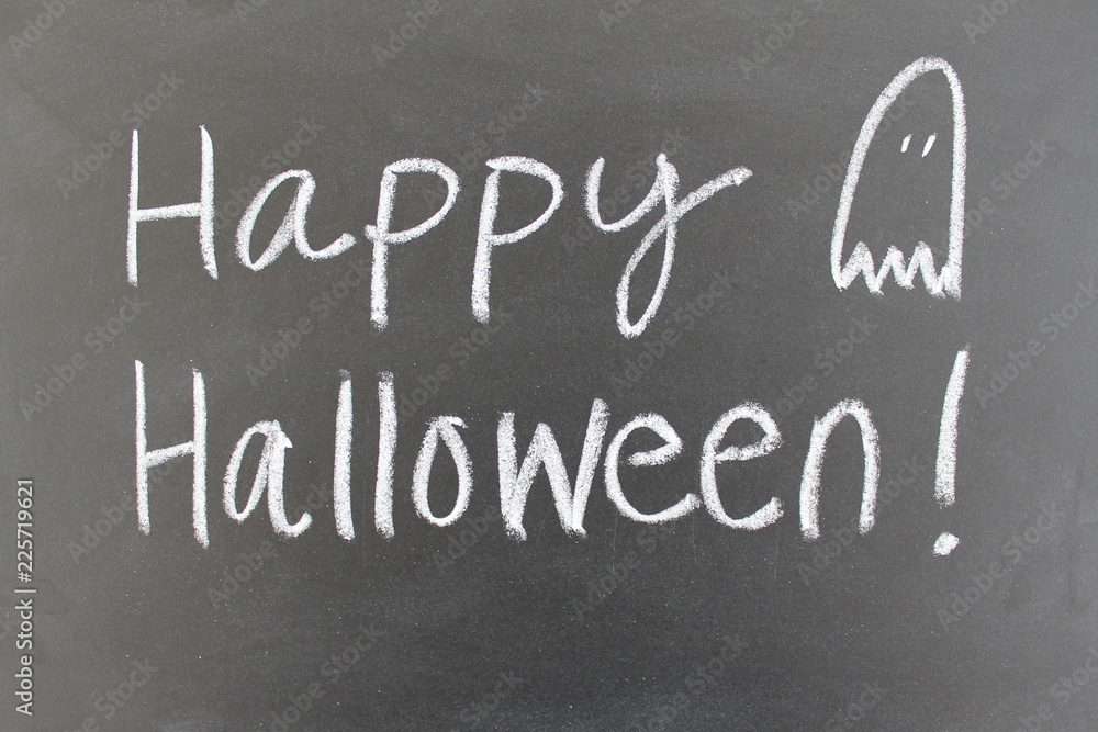 Obraz premium Happy Halloween handwritten on a blackboard with a ghost doodle.