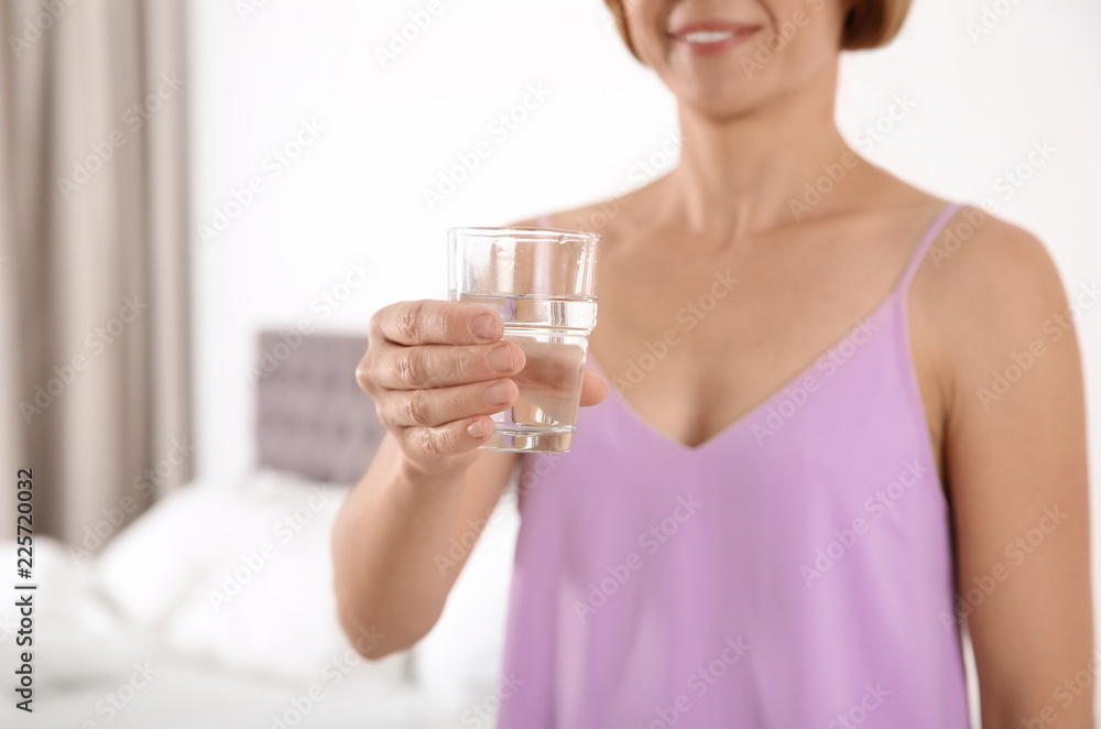 Woman holding glass with clean water in bedroom, closeup. Space for text Woman holding glass with clean water in bedroom, closeup. Space for text
