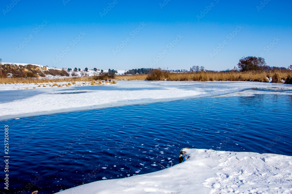 Winter landscape: the river on a sunny day, the banks of the river, covered with snow_