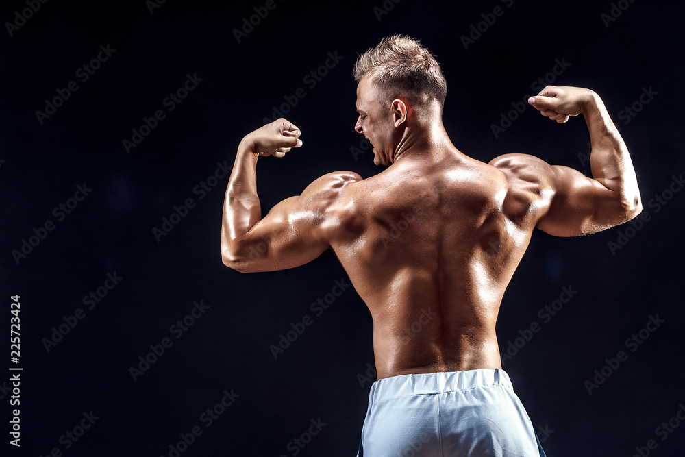 Fototapeta premium Handsome strong bodybuilder posing in studio on black background