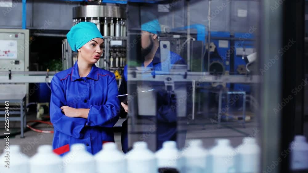 Man and woman stand near the conveyor belt with plastic bottles Man and woman stand near the conveyor belt with plastic bottles