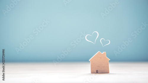 Home sweet home, house wood with heart shape on wooden and blue background, copy space.