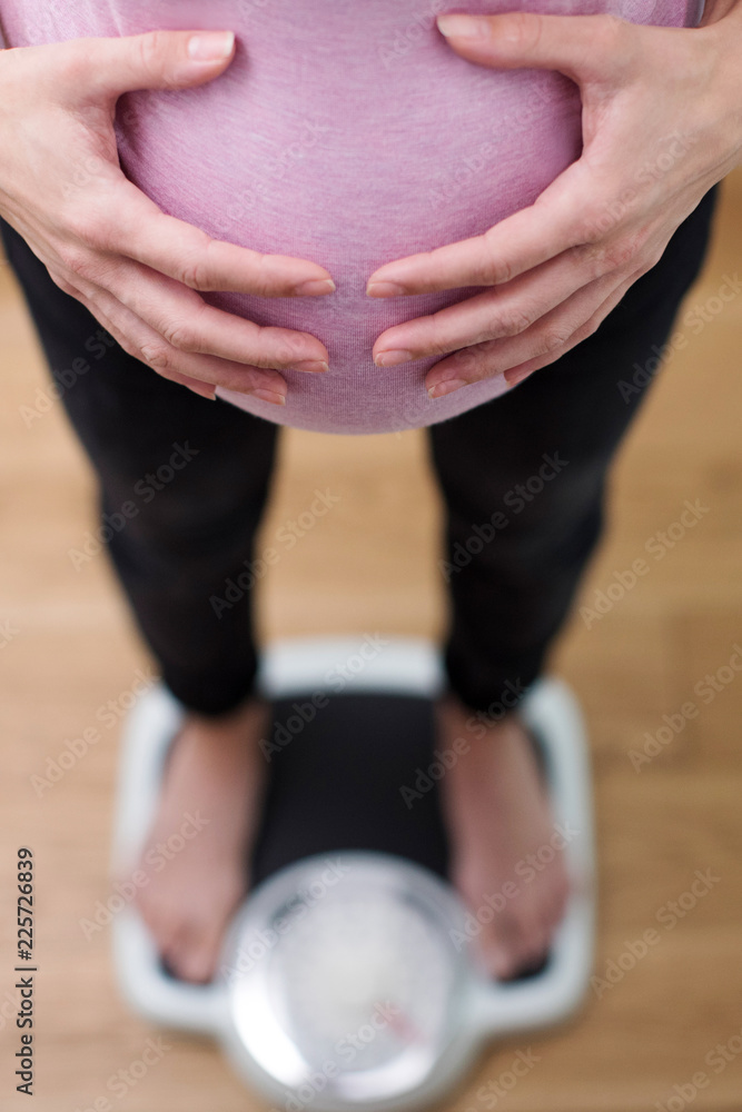 Naklejka premium Close Up View Looking Down On Pregnant Woman Standing On Bathroom Scales