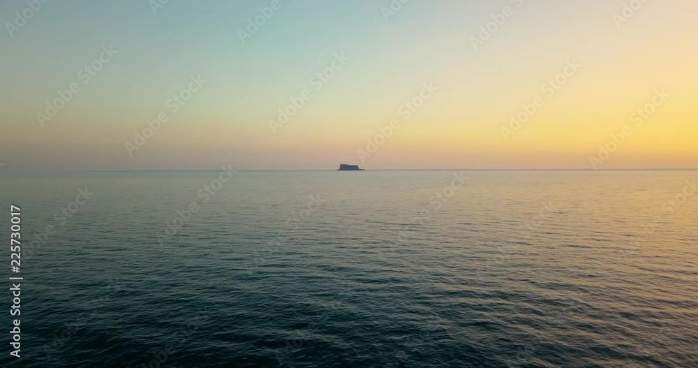 Aerial dron view of beautiful calm sea and small island in the middle of the sea on yellow sunset. Malta Aerial dron view of beautiful calm sea and small island in the middle of the sea on yellow sunset. Malta