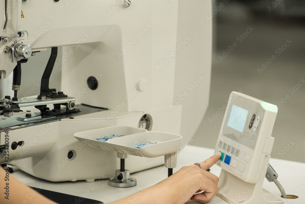 seamstress at work, controls the sewing machine through an electronic panel