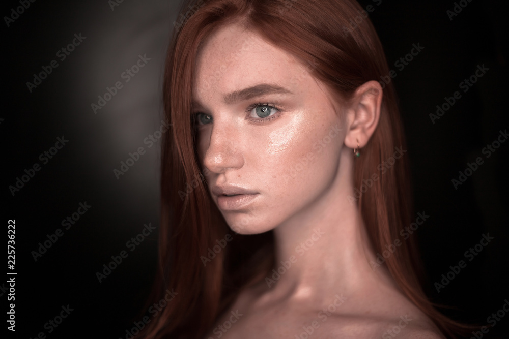 Beautiful serious redhead girl woman with healthy glow wet skin posing isolated over black wall background looking aside to empty copyspace. Beautiful serious redhead girl woman with healthy glow wet skin posing isolated over black wall background looking aside to empty copyspace.