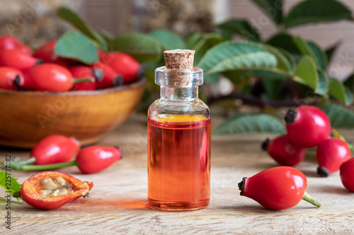 A bottle of rosehip seed oil with fresh rosehips